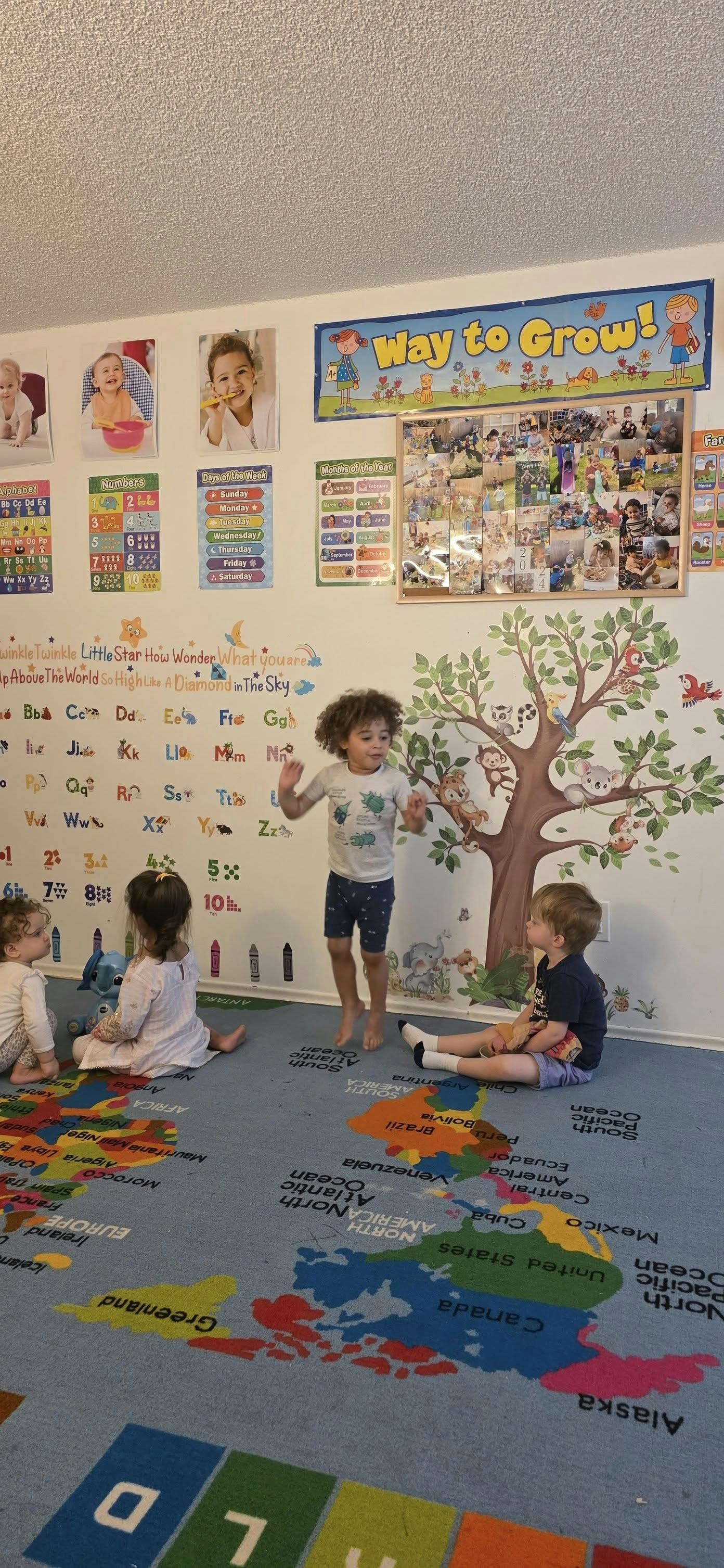Child jumping while other children sit on a map rug in a classroom