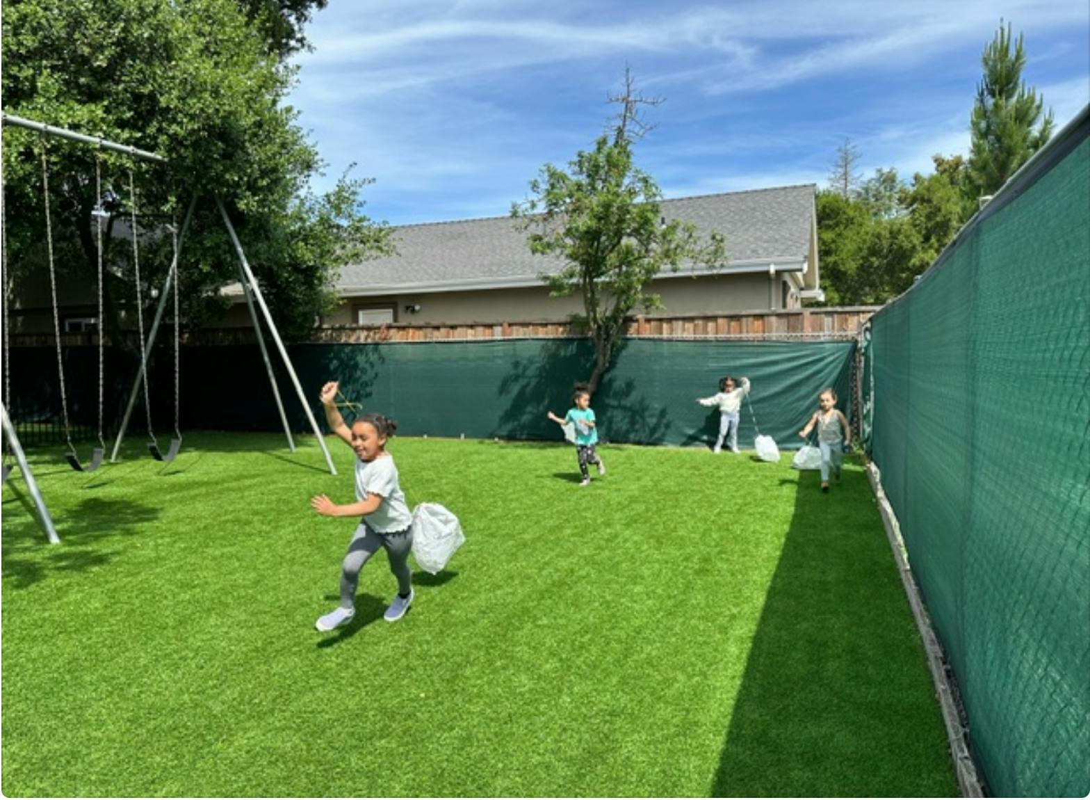 Children running on grass with white bags