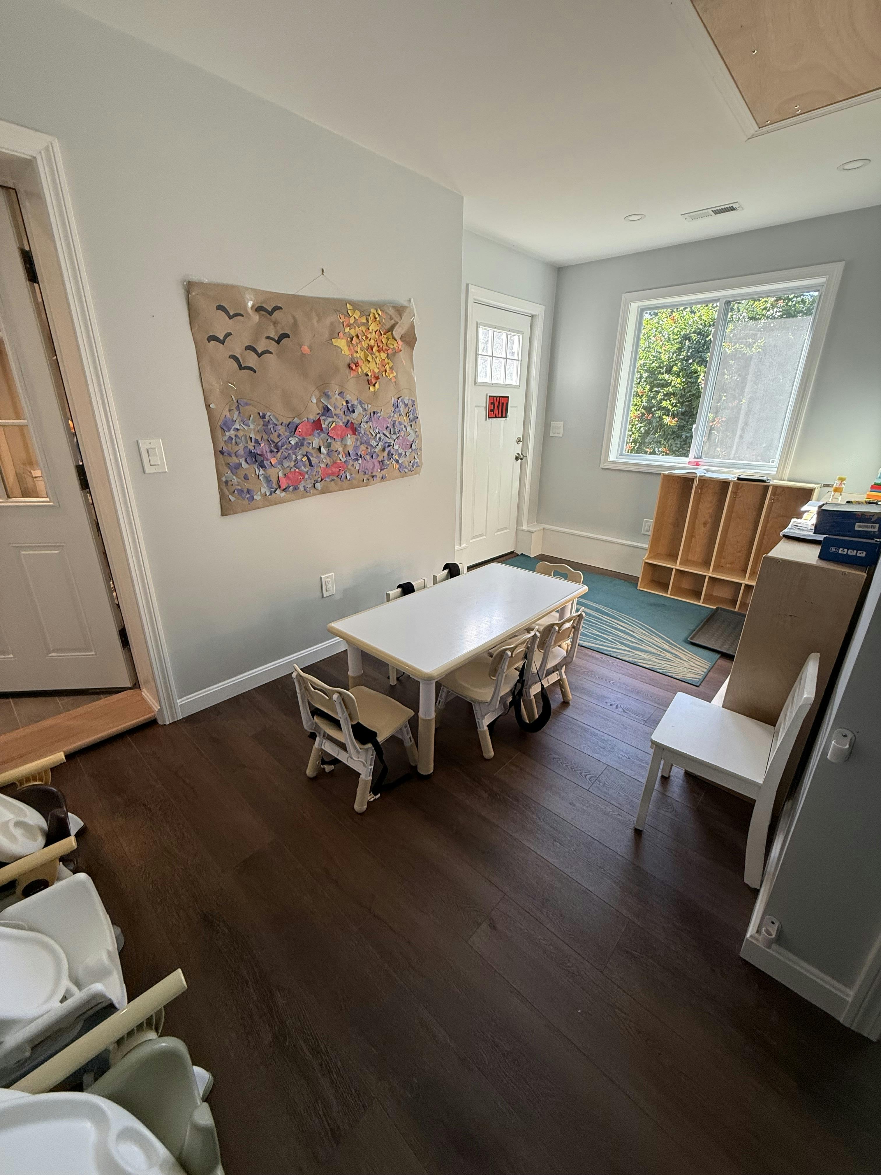A classroom with a small table and chairs, and an art project on the wall
