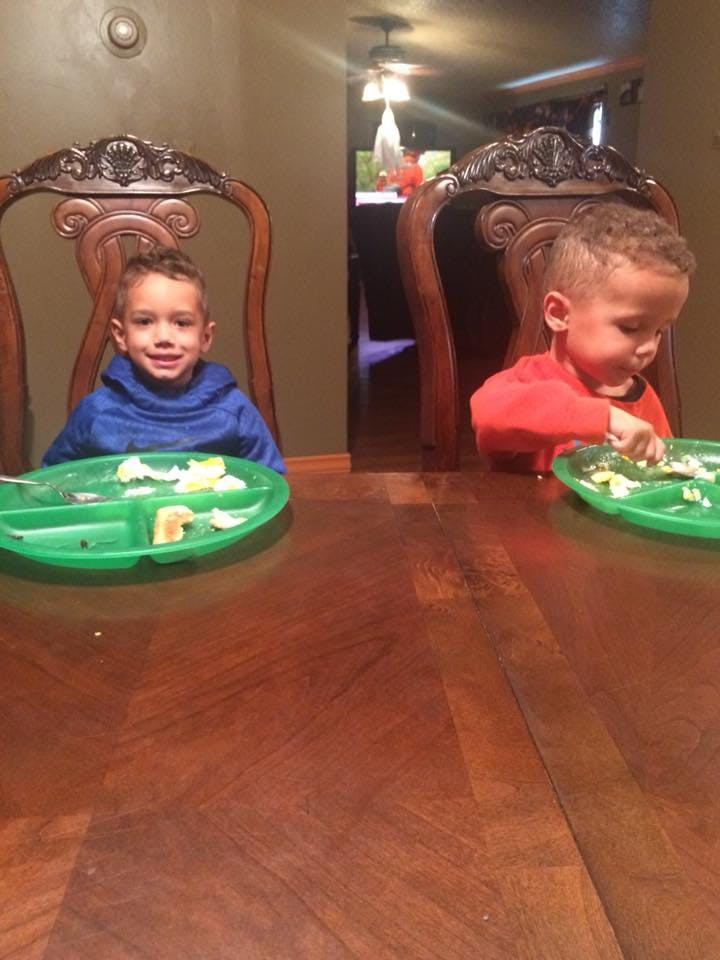 Two children sitting at a table with green plates of food