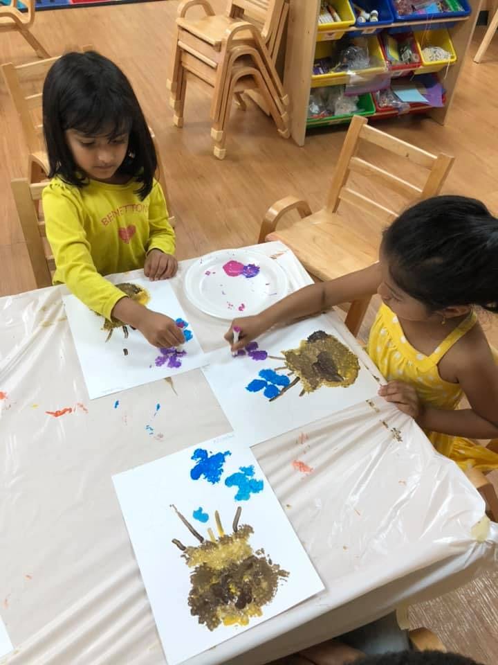 Two children painting with their fingers at a table