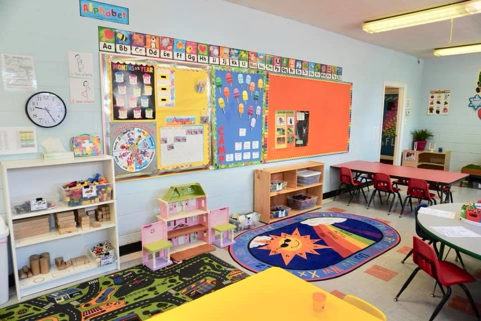 Classroom with colorful decorations, small tables, and play areas