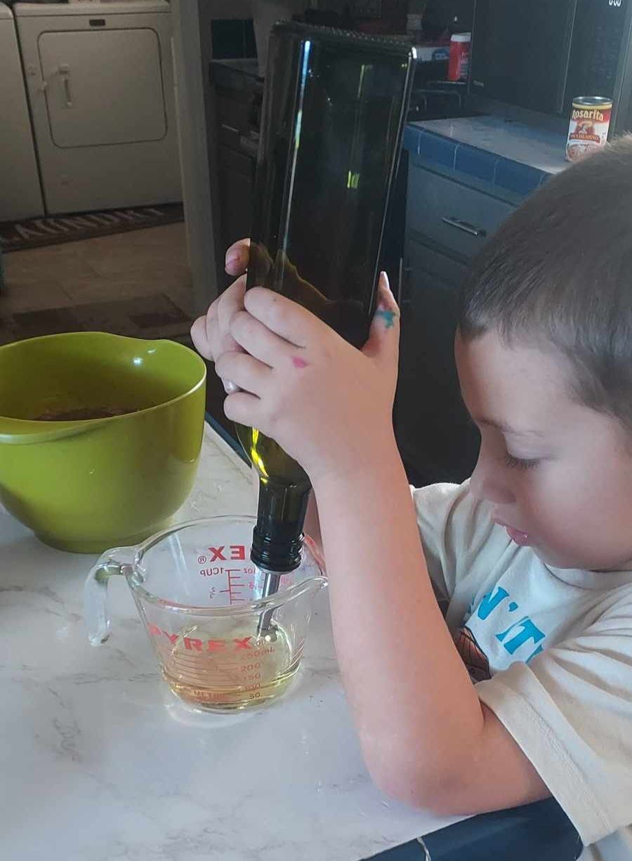 Child pouring liquid from a bottle into a measuring cup