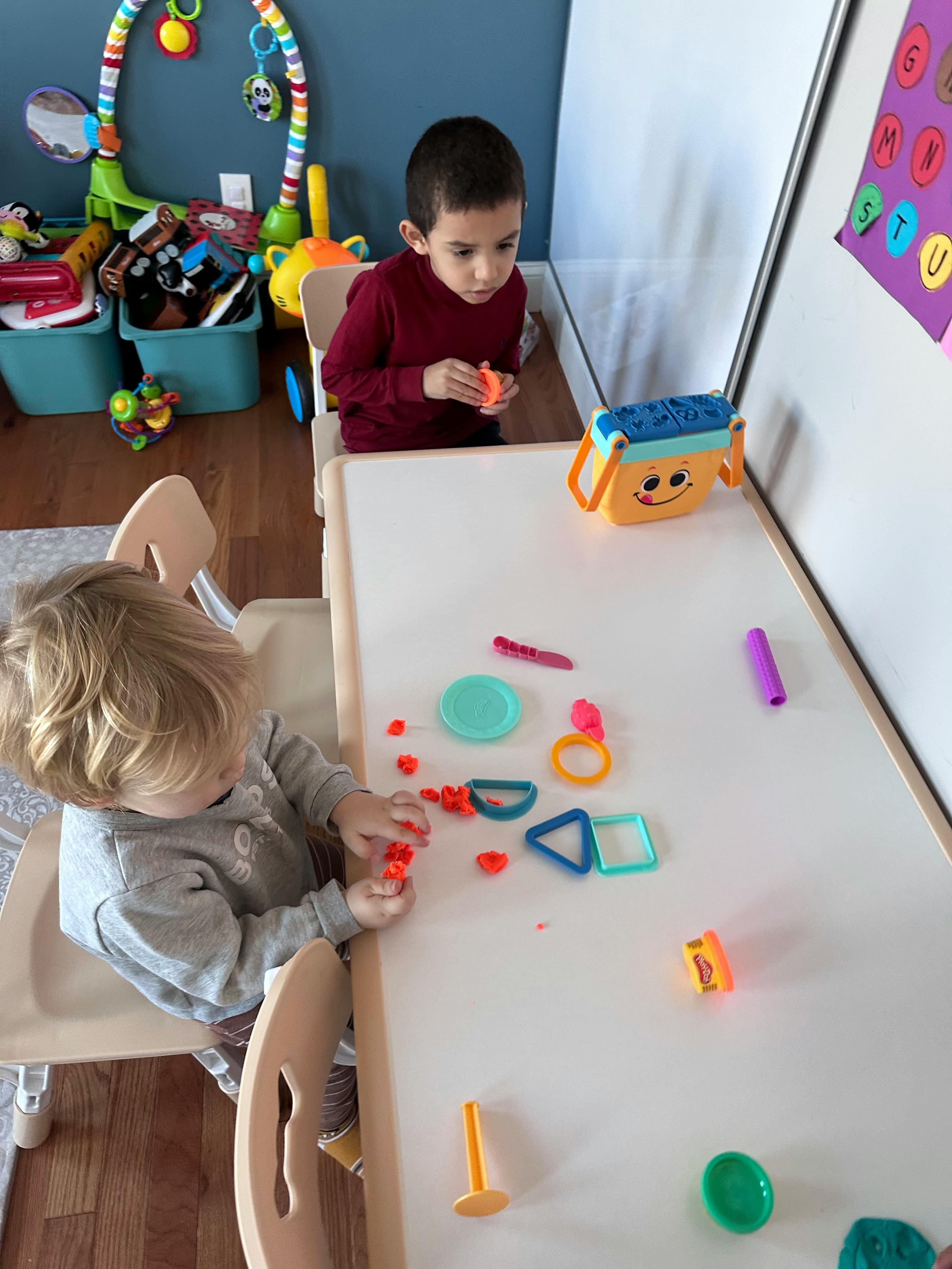 Two children playing with modeling clay at a table