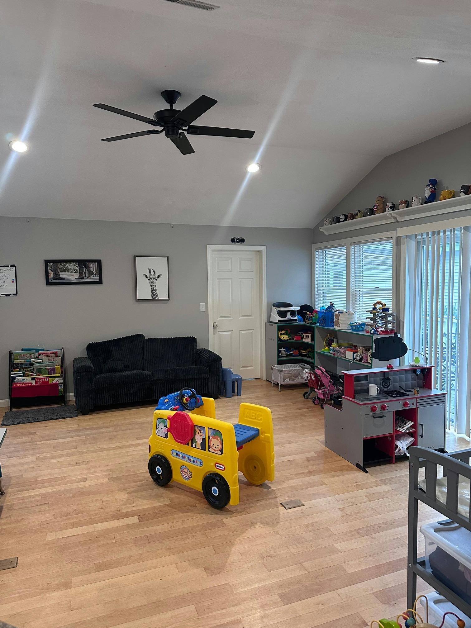 Playroom with a toy bus, play kitchen, and assorted toys on a wood floor