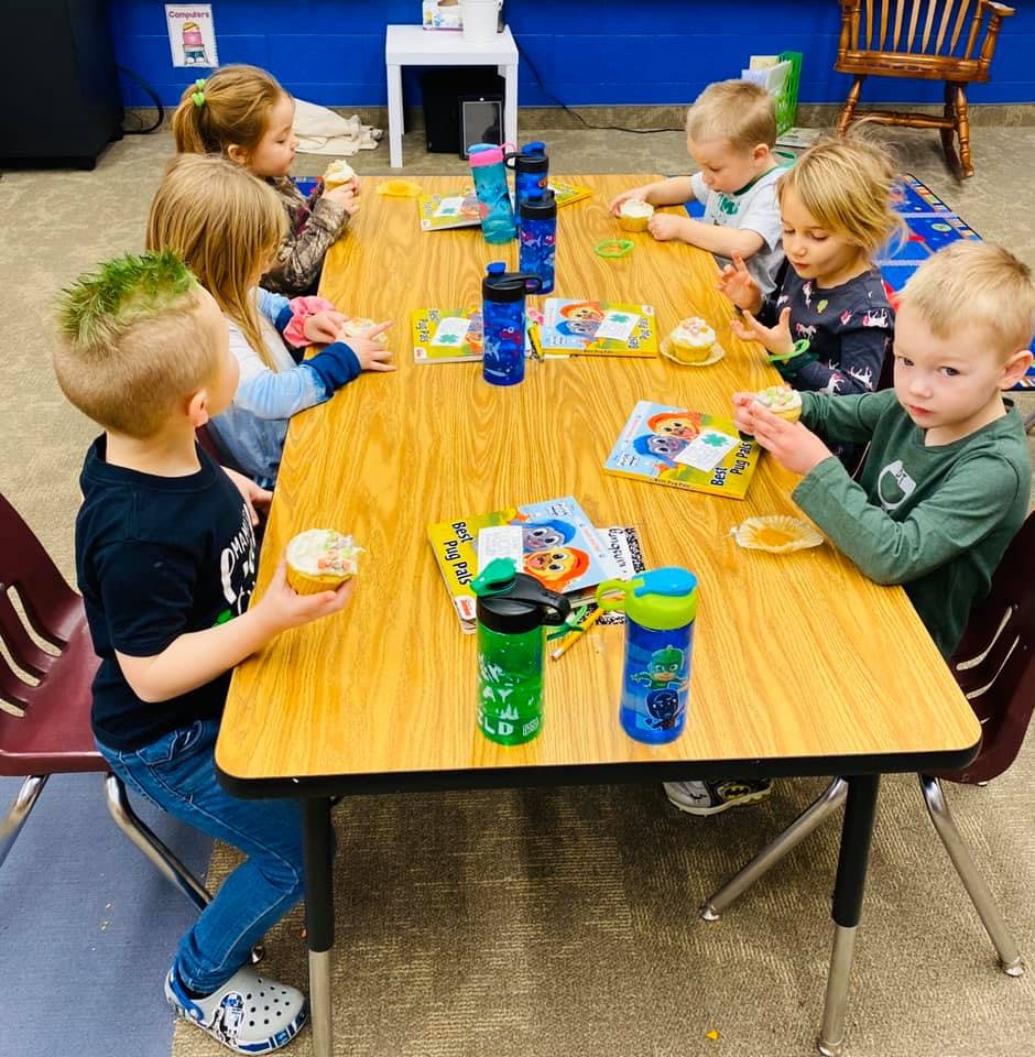 Children sitting at a table with snacks and water bottles