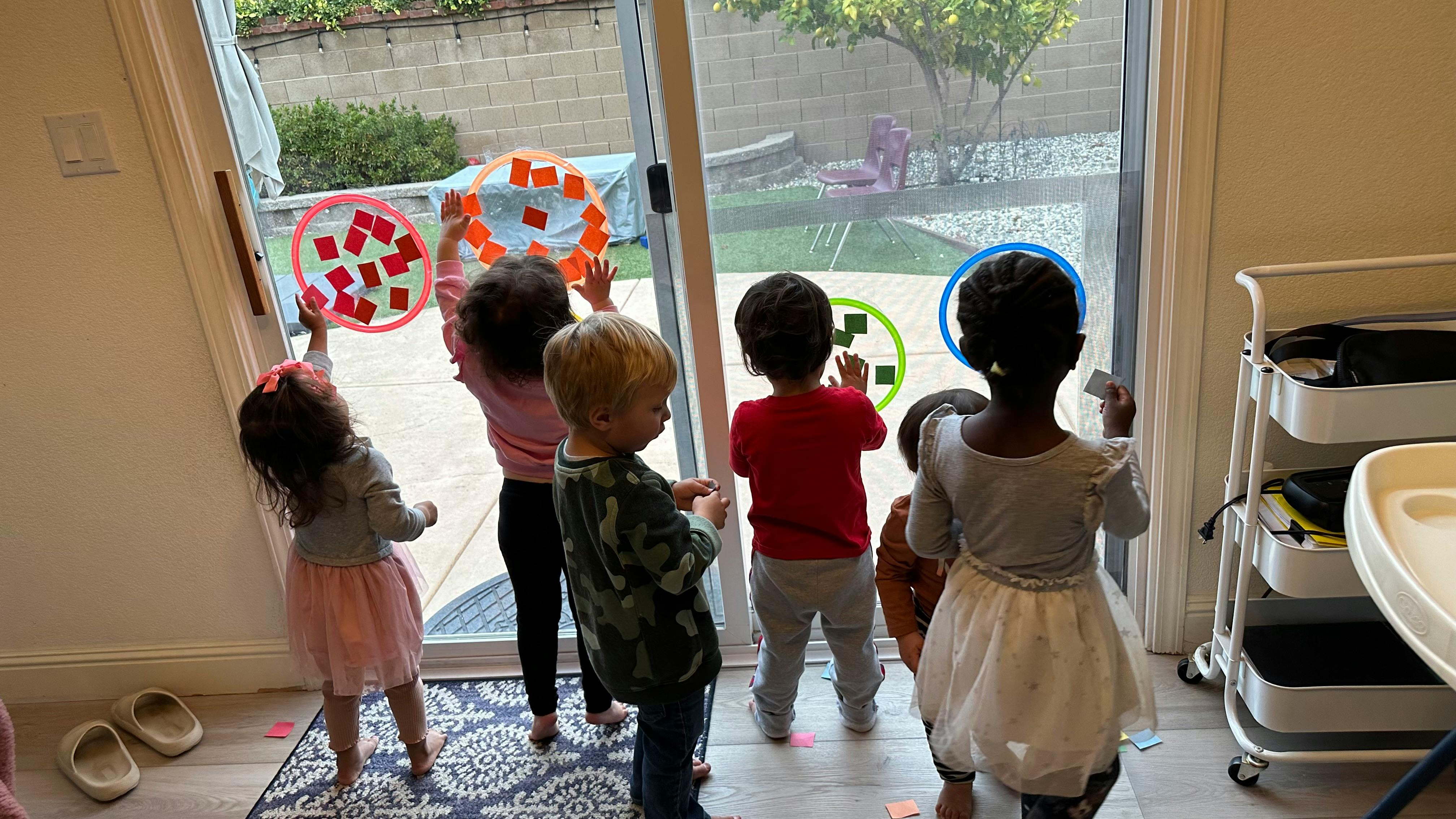 Children playing with colorful objects on a glass door