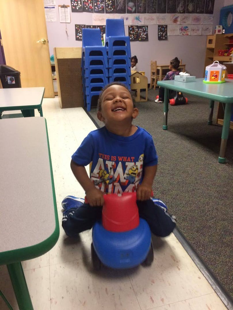 Child riding a toy in a classroom