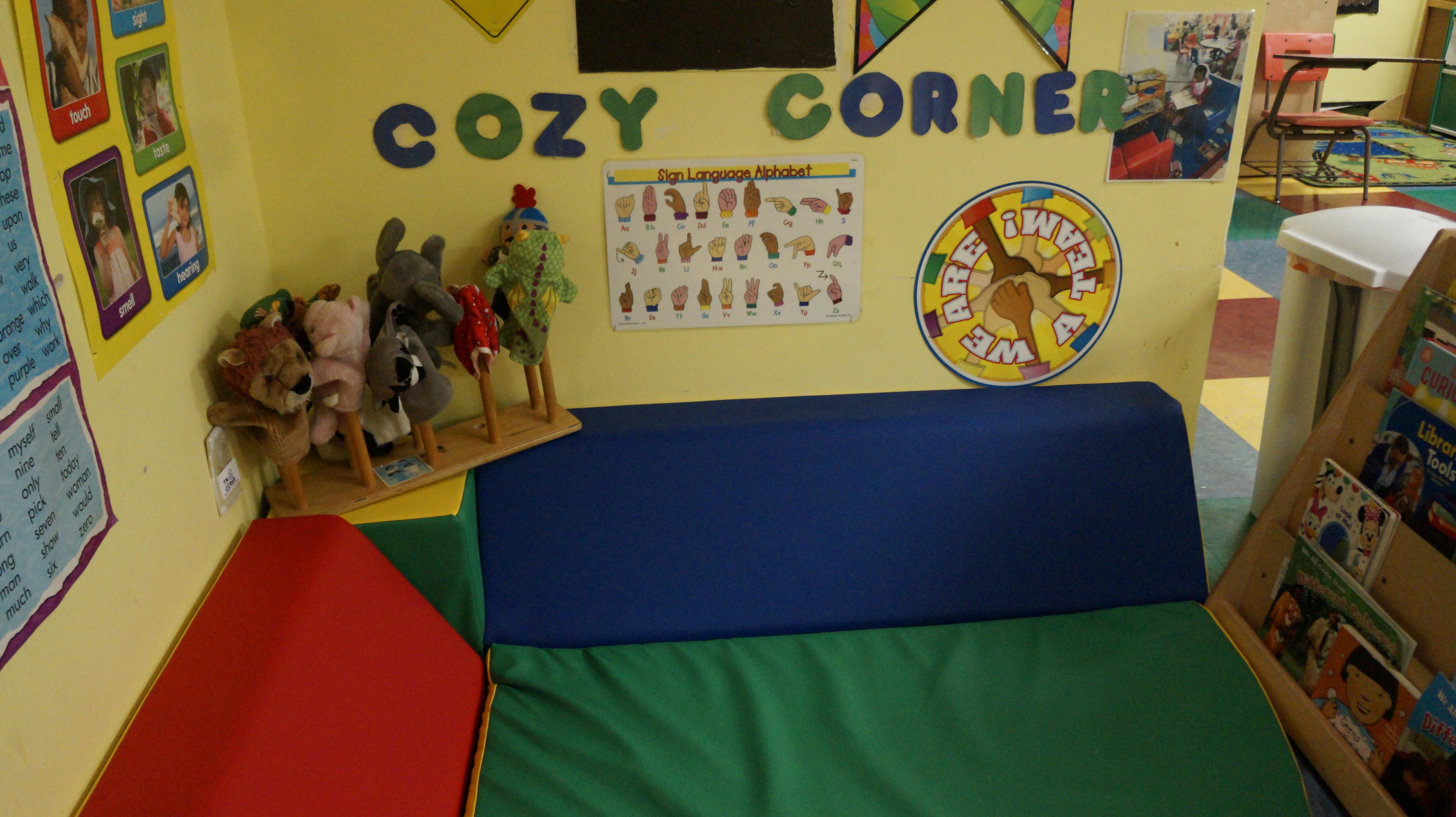Classroom corner with soft seating and wall decorations including text "COZY CORNER"