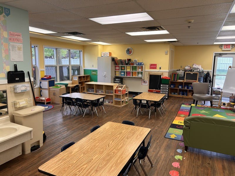 Classroom with small tables and chairs, shelves, and a play kitchen