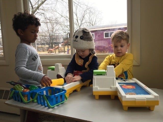 Three children playing with toys on a table