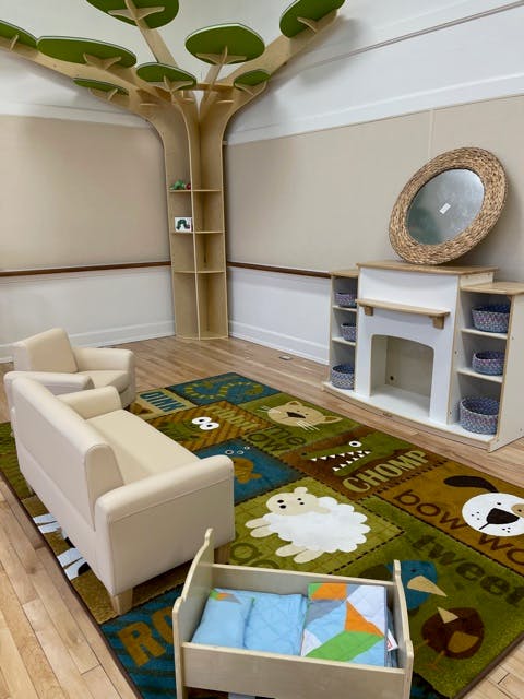 Playroom with a tree-shaped bookshelf, small sofa, and animal-themed rug