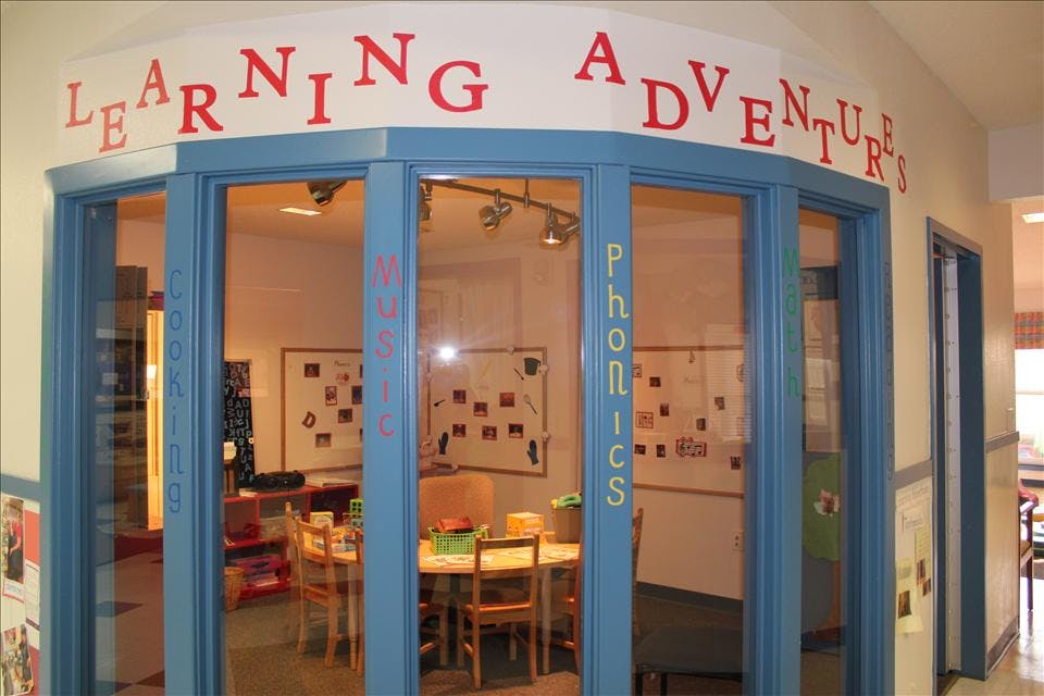 Classroom entrance with "Learning Adventures" above, doors labeled "Cooking," "Music," "Phonics"