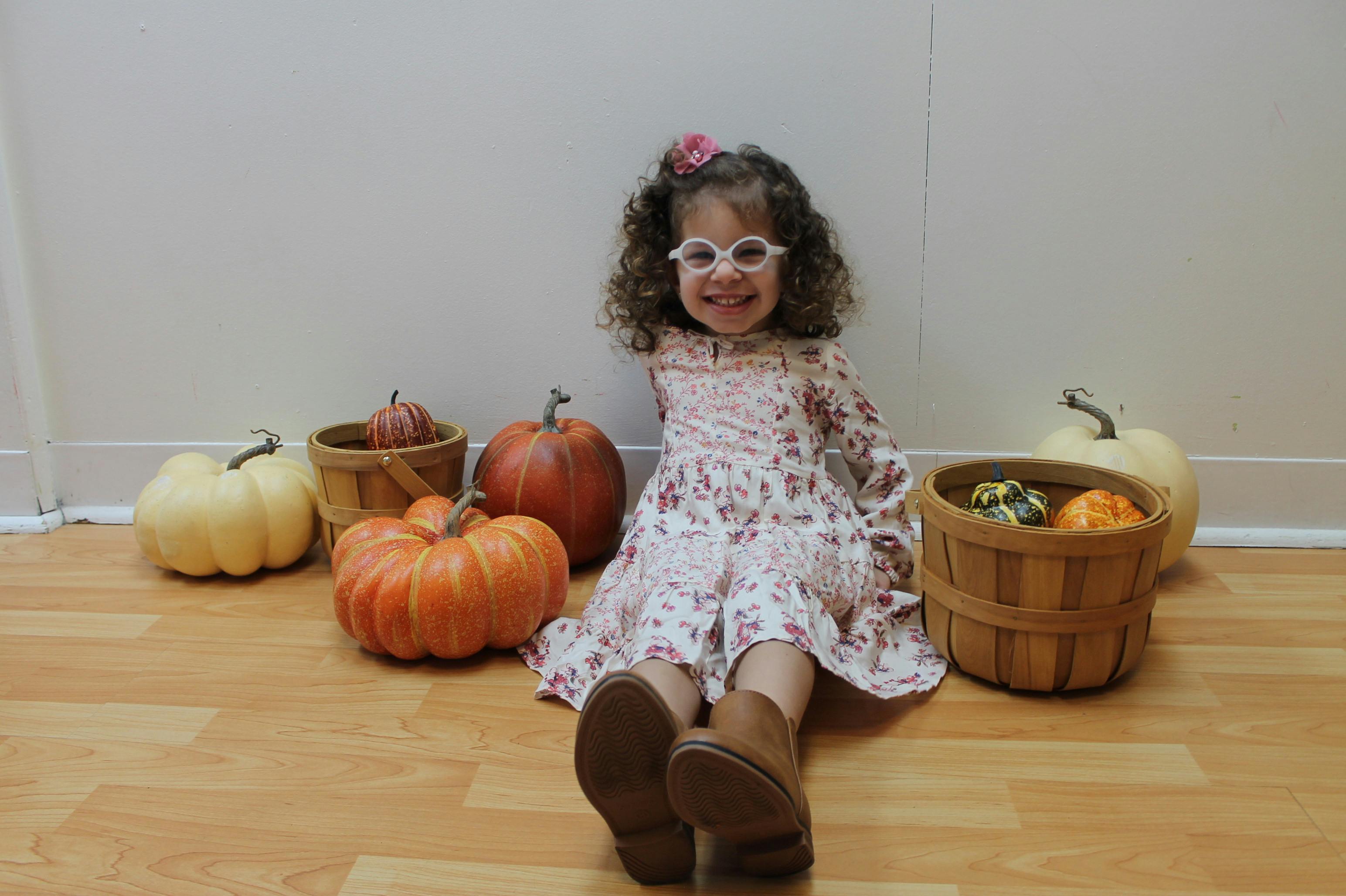 Child sitting on floor with pumpkins and gourds