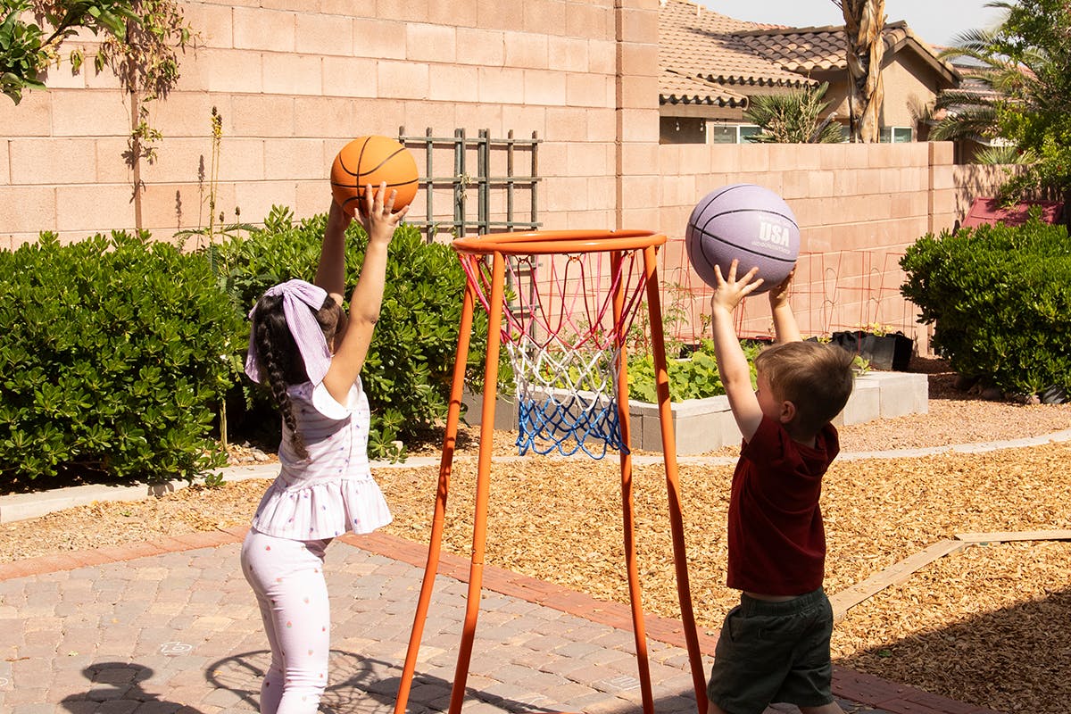 Two children playing basketball with a small hoop