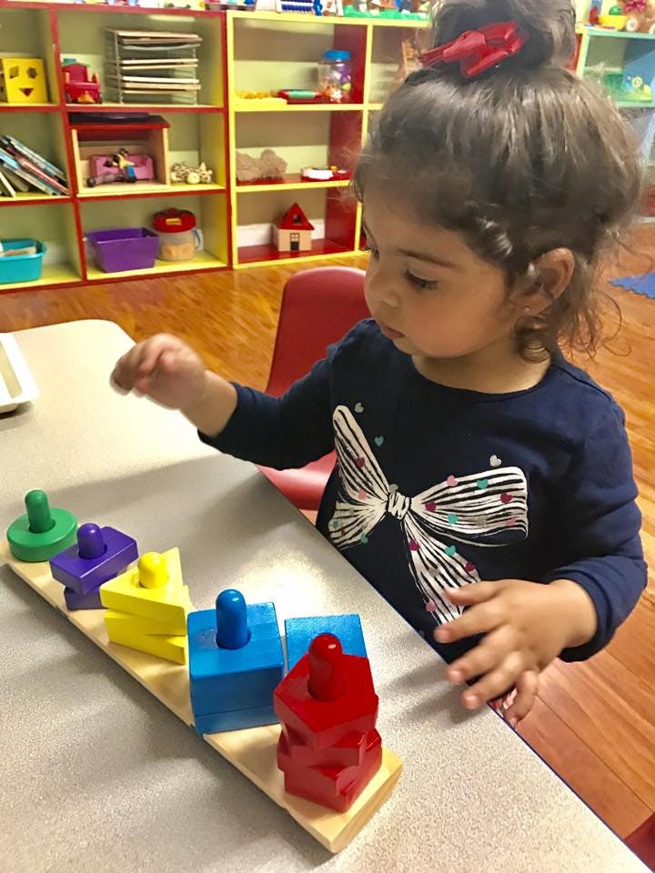 Child playing with a colorful shape sorter toy at a table