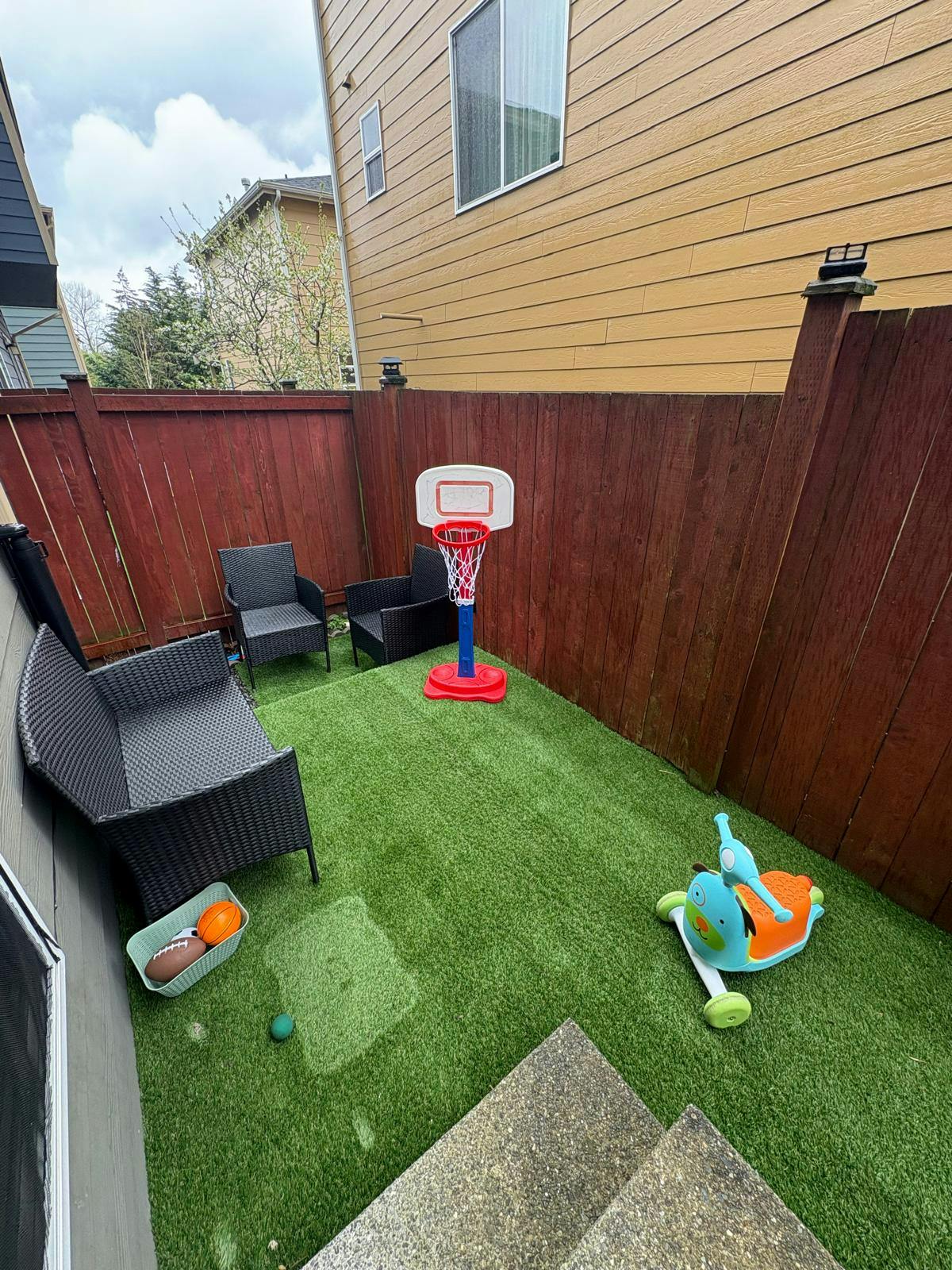 Backyard with artificial turf, small basketball hoop, and outdoor furniture