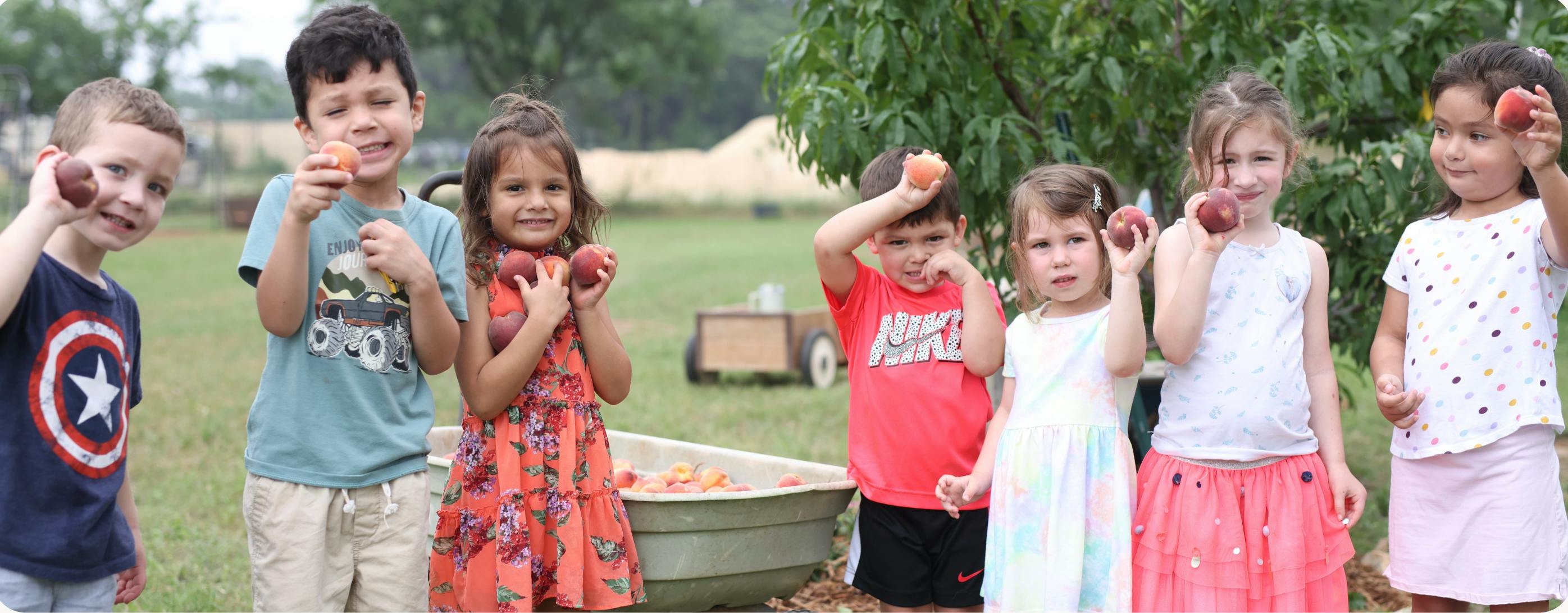 Group of children holding fruit outdoors