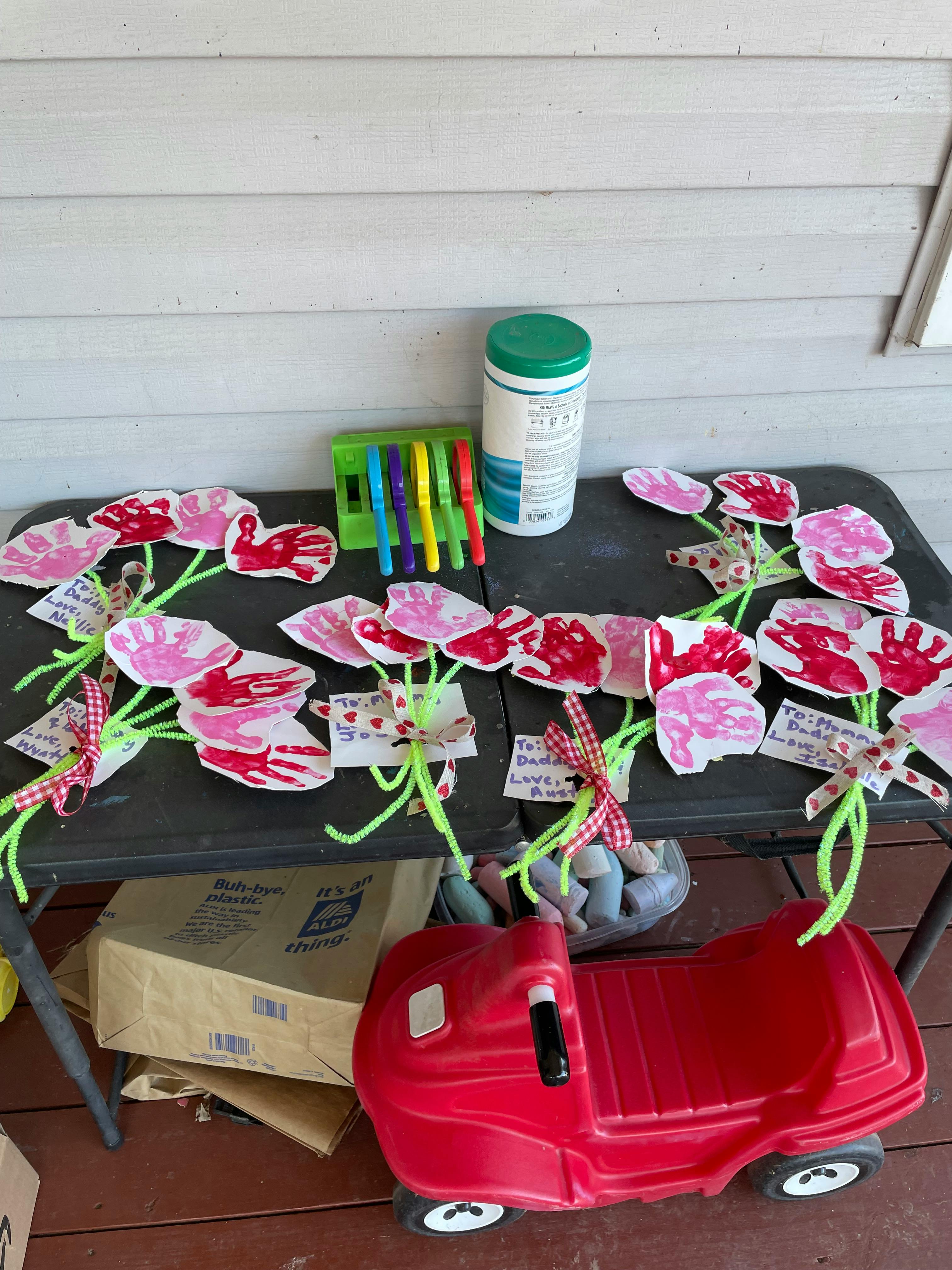 Table with handprint crafts, a container, and a toy car