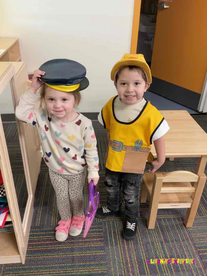 Child in construction worker costume next to a child wearing two hats