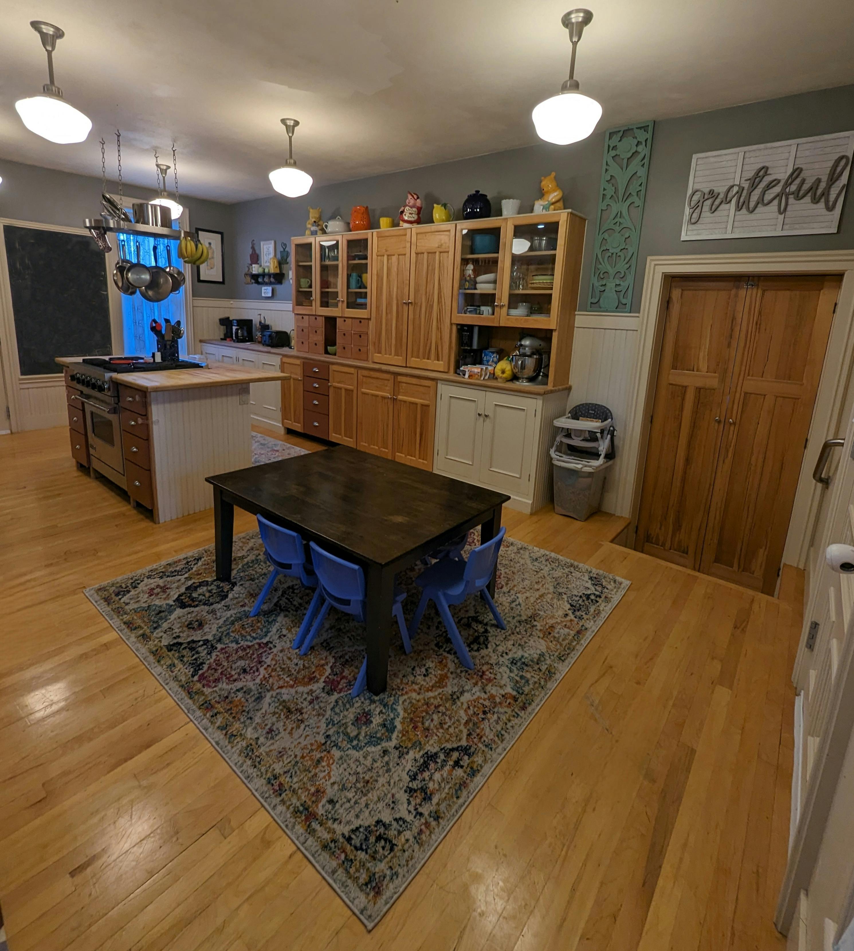 Kitchen with wooden cabinets, island, and dining table with blue chairs