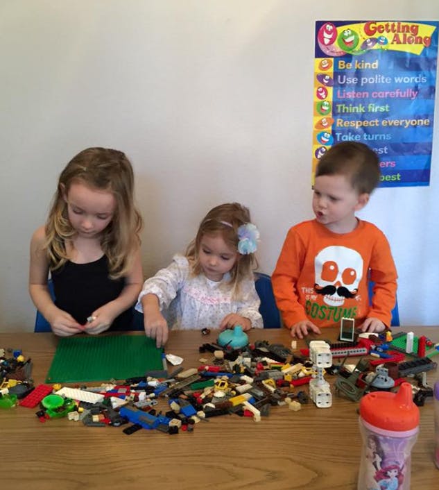 Three children playing with building blocks at a table