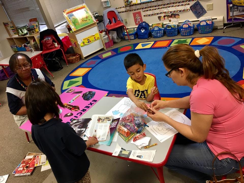 Adults and children at a table in a classroom