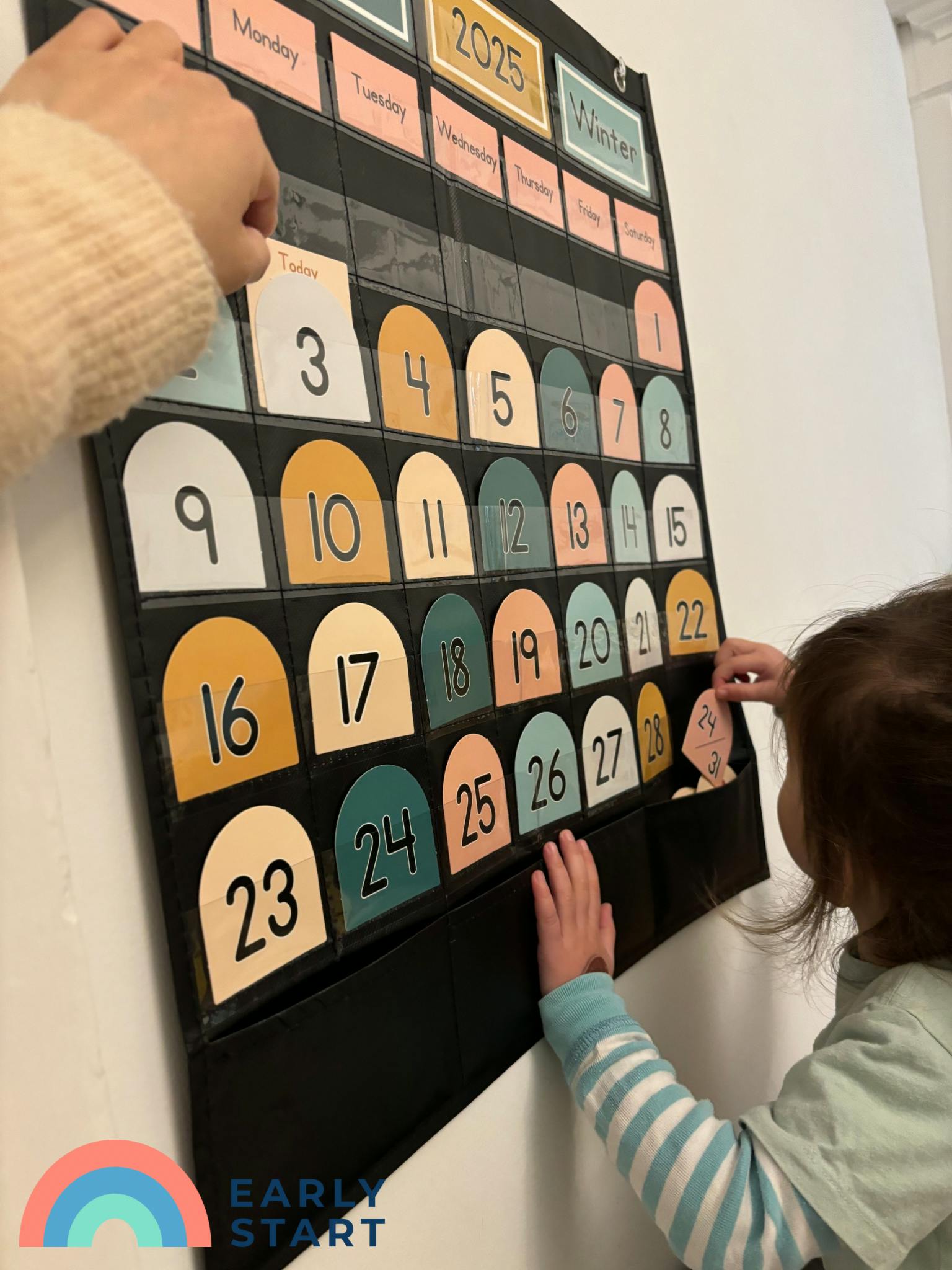 Person and child interacting with a wall calendar with numbered cards