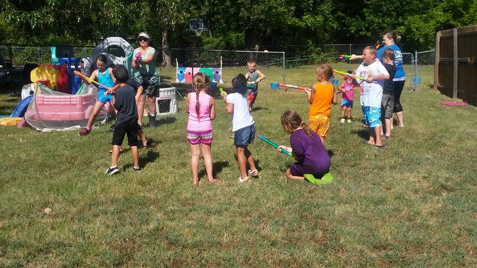 Children and adults playing with water guns outdoors