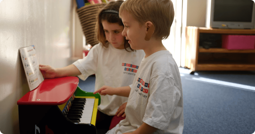Two children looking at sheet music on a toy piano