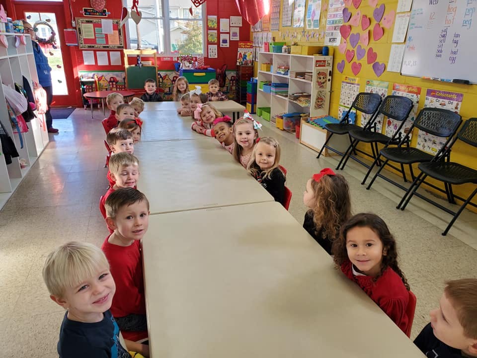Children sitting at a long table in a classroom