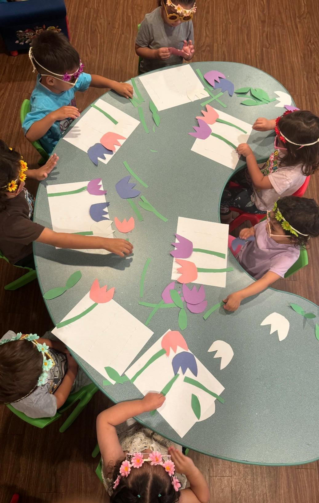 Several children at a table making paper flower crafts