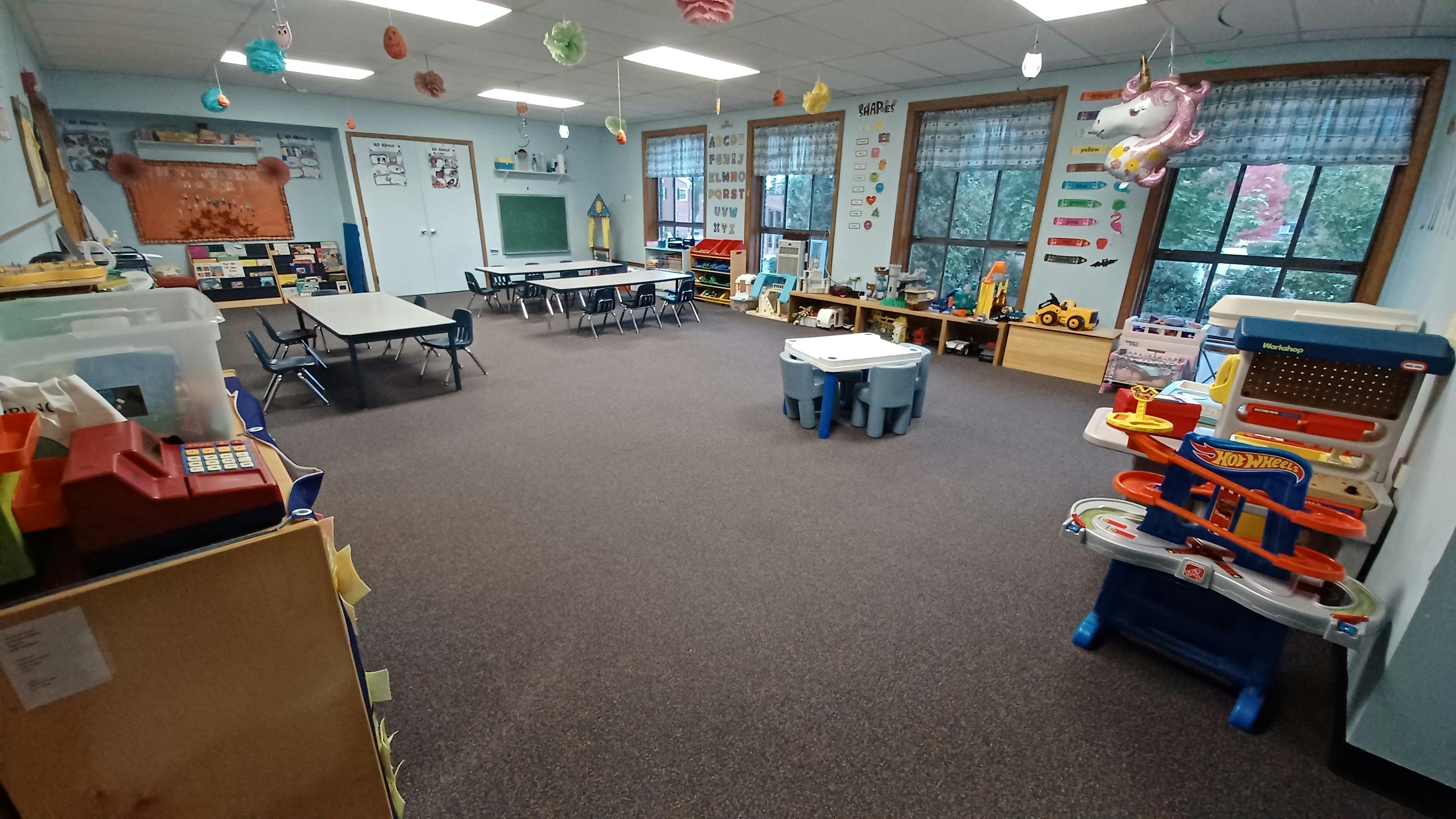 Empty classroom with tables, chairs, and toys