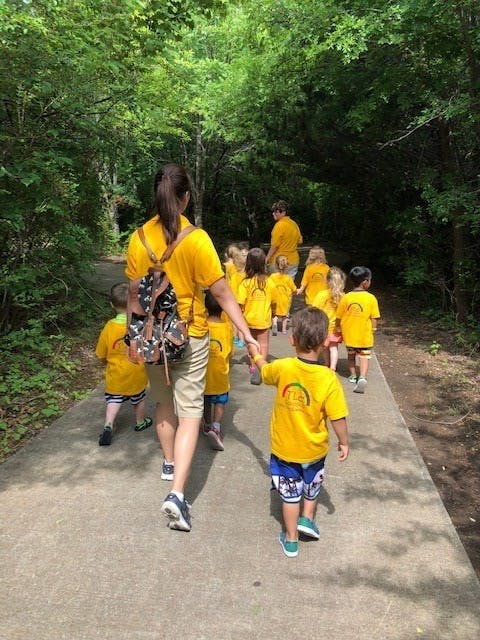 Adult and children in yellow shirts walking on a path