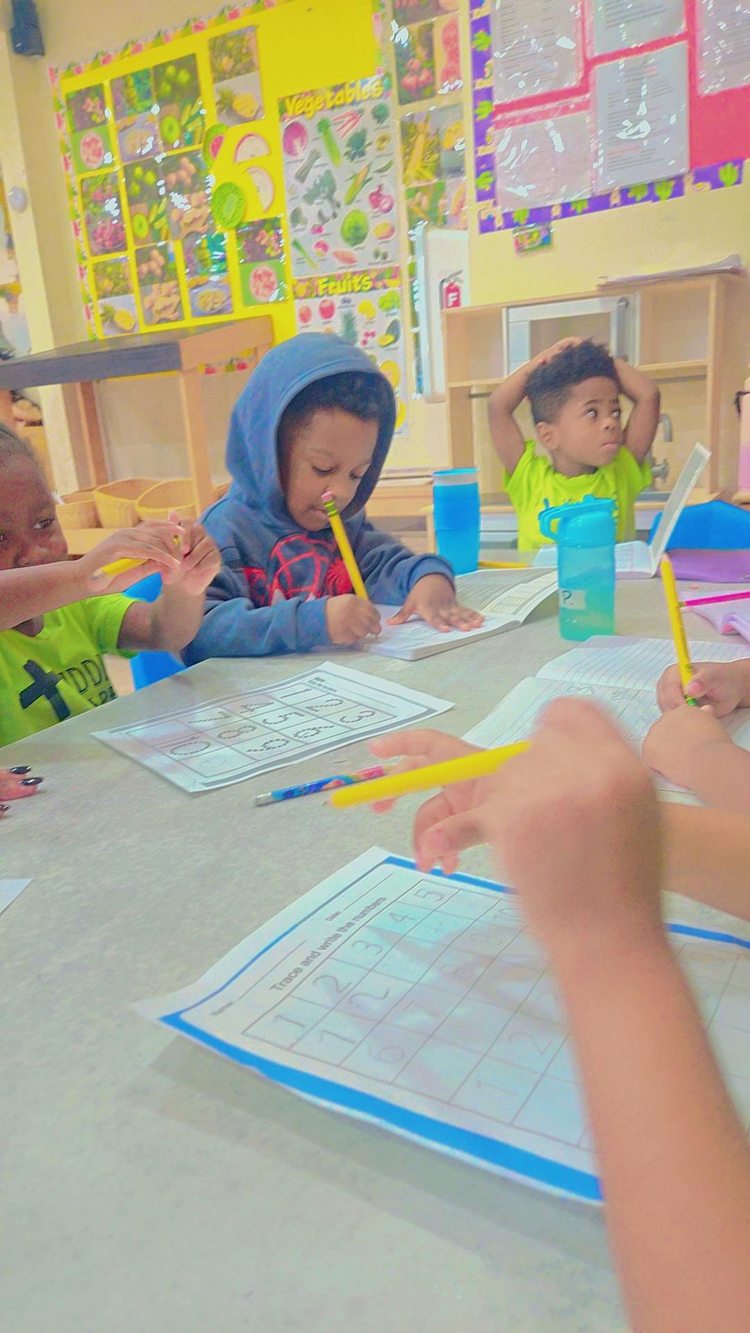Children writing at a table in a classroom