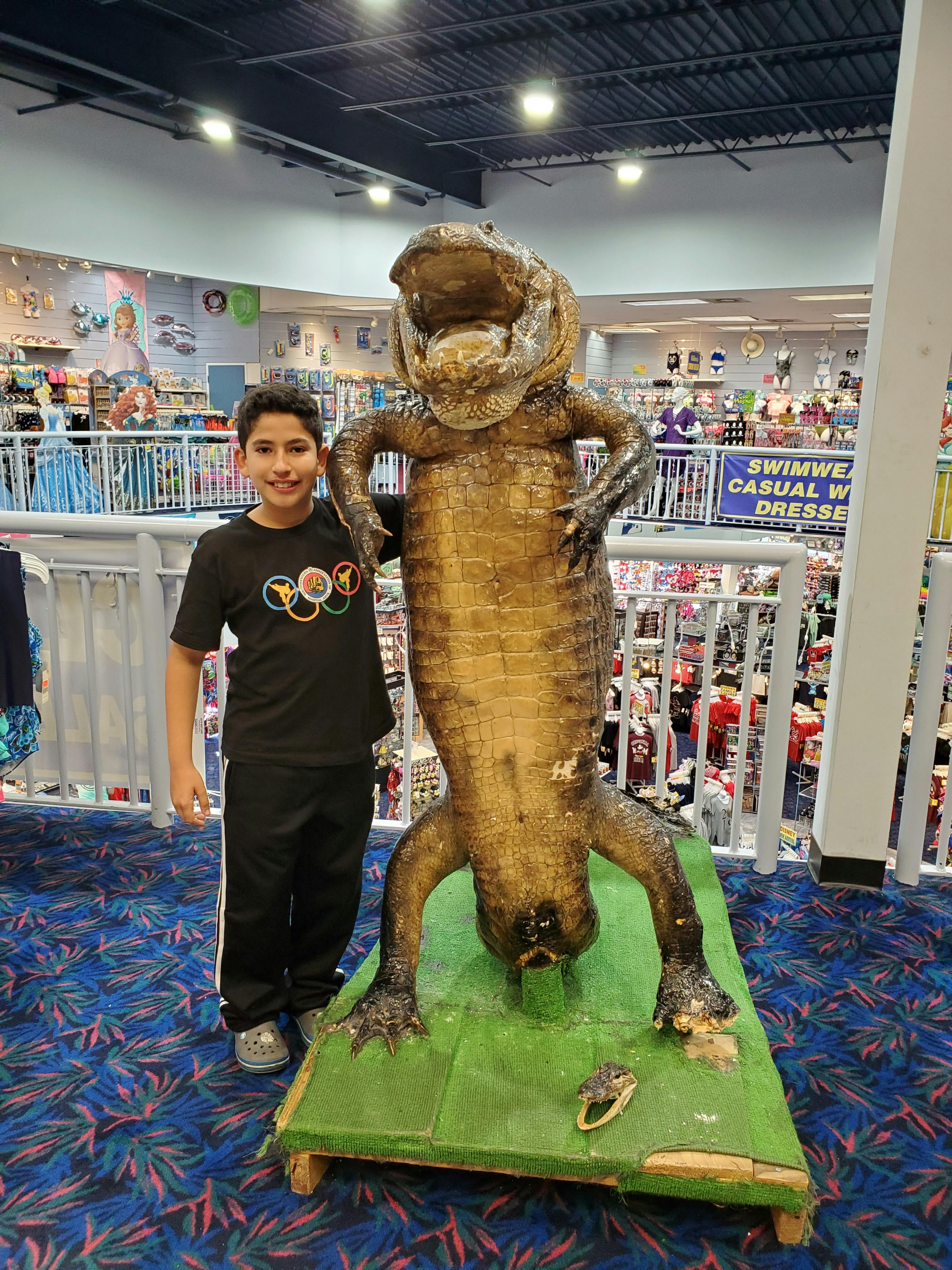 Teen standing next to a large alligator statue