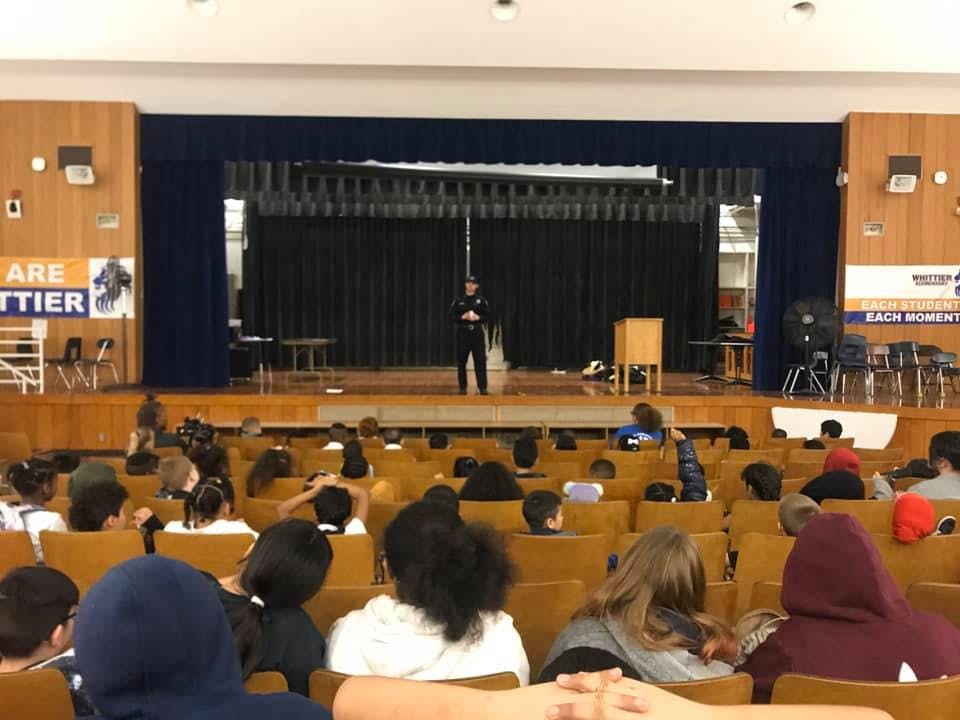Person on stage speaking to an audience of children and teens