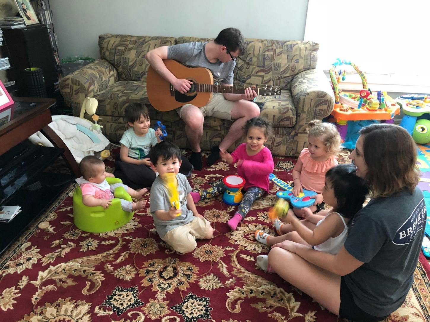 Person playing guitar for a group of children and adults