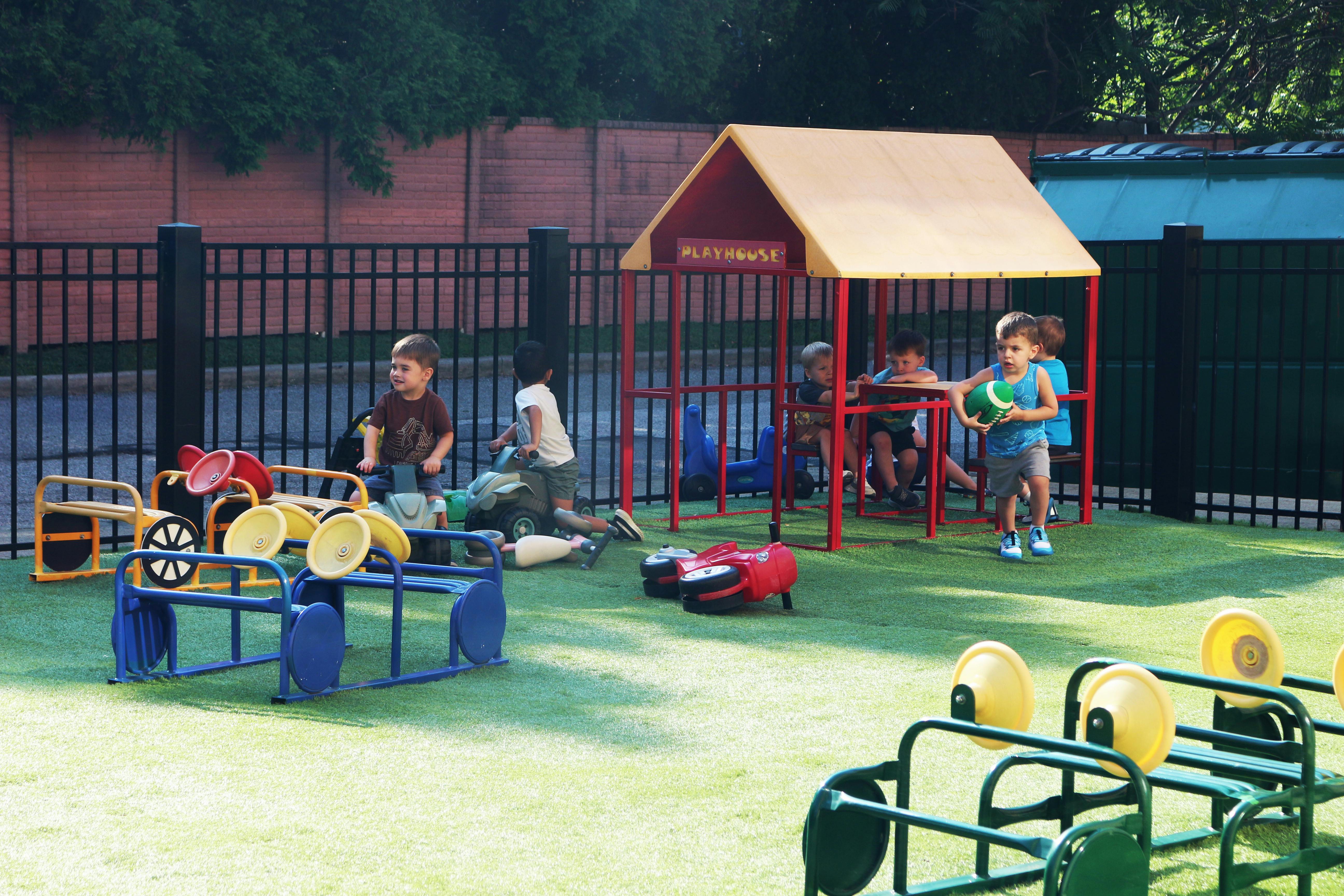 Children playing on a playground with a small playhouse