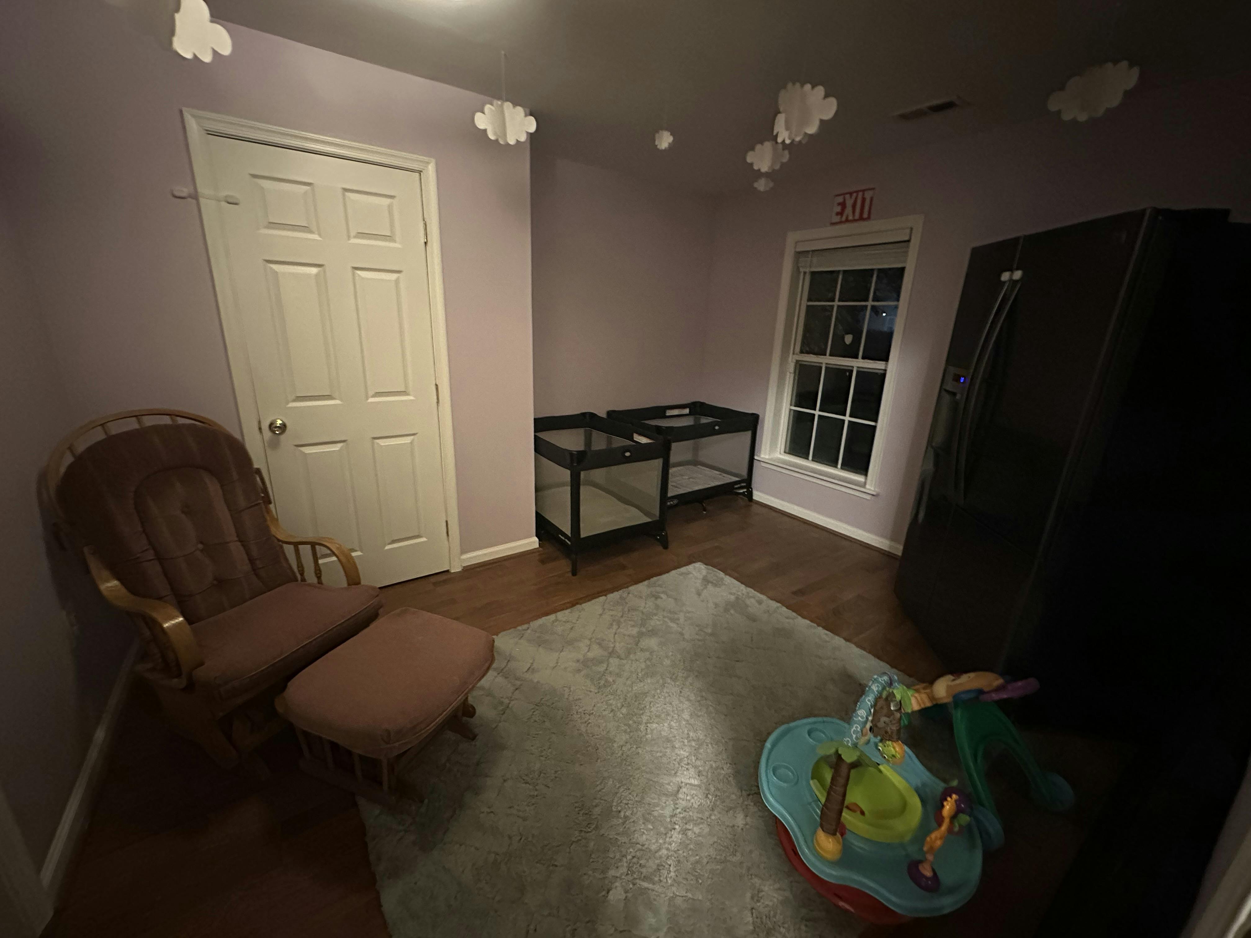 Room with a chair, ottoman, and baby play mat on a rug
