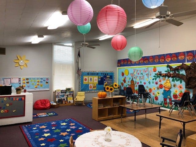Classroom with colorful paper lanterns, small tables and chairs, and wall decorations