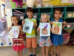Four children holding up their drawings