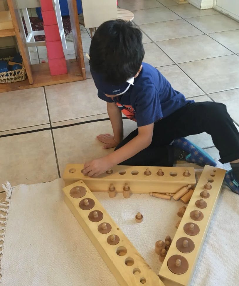 Child playing with wooden cylinder blocks on a rug