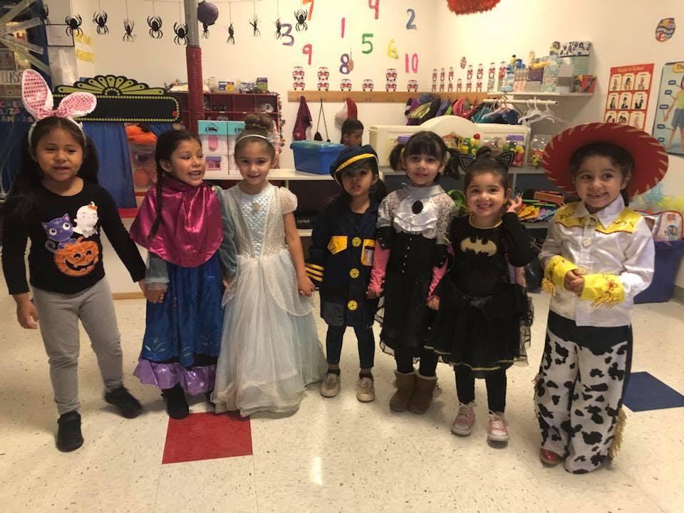 Seven children in various costumes standing in a room