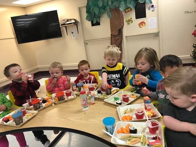 Group of children eating snacks at a table in a classroom