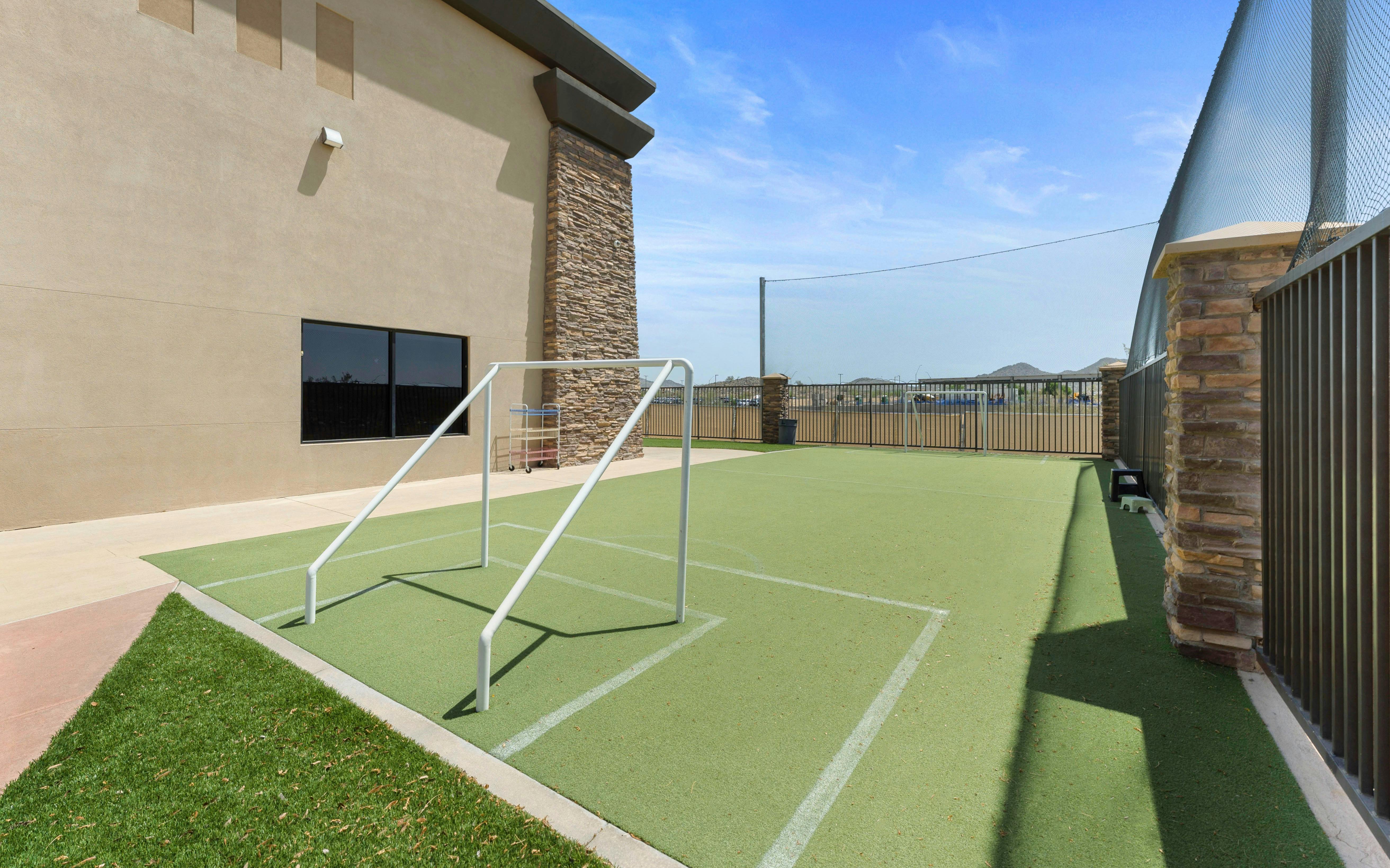 An outdoor playground with a green turf surface and small white soccer goals