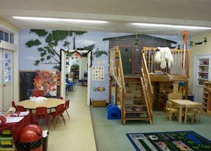 Playroom with tables, chairs, and a wooden play structure