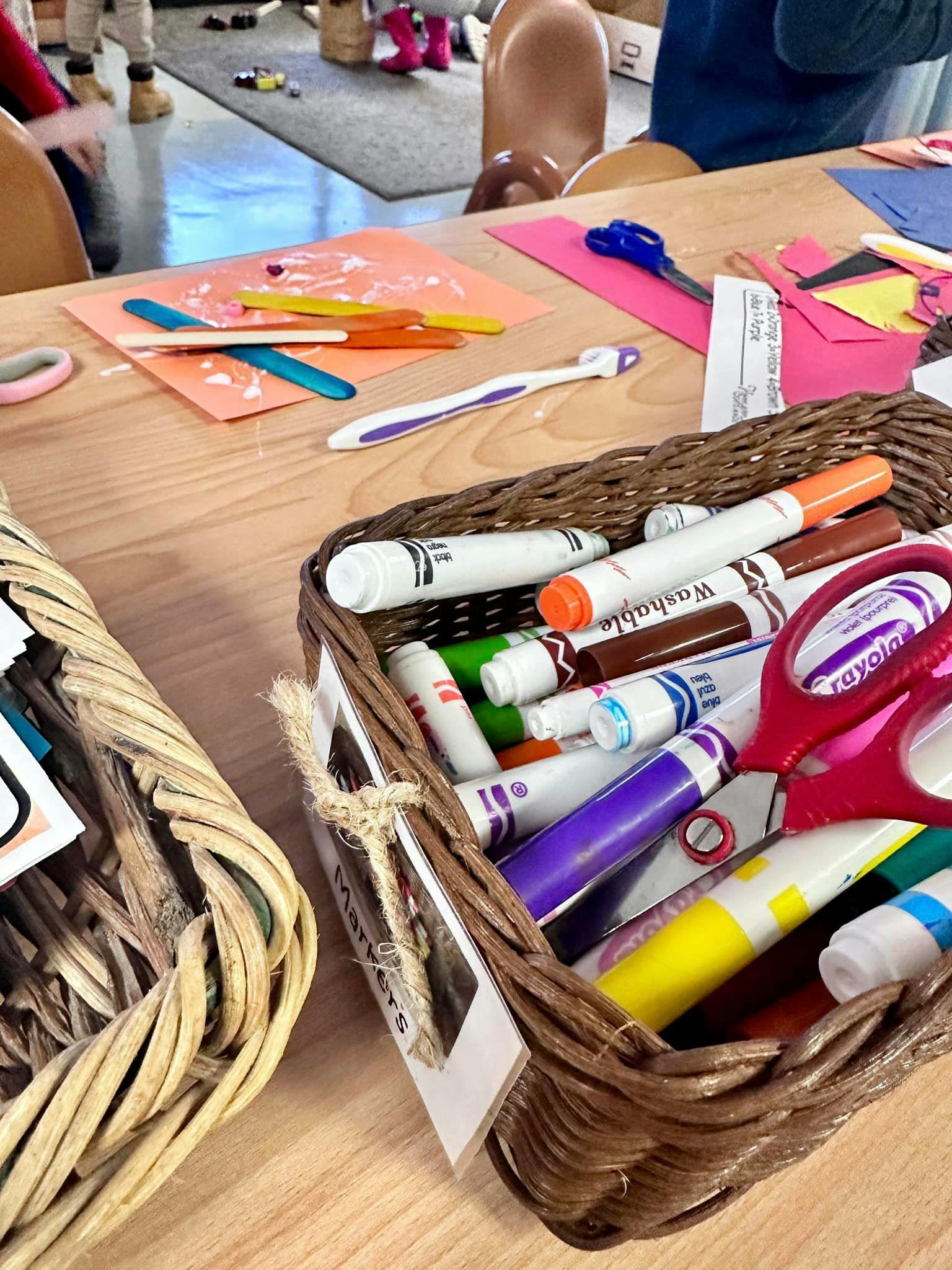 Craft supplies on a wooden table, including markers, scissors, and paper