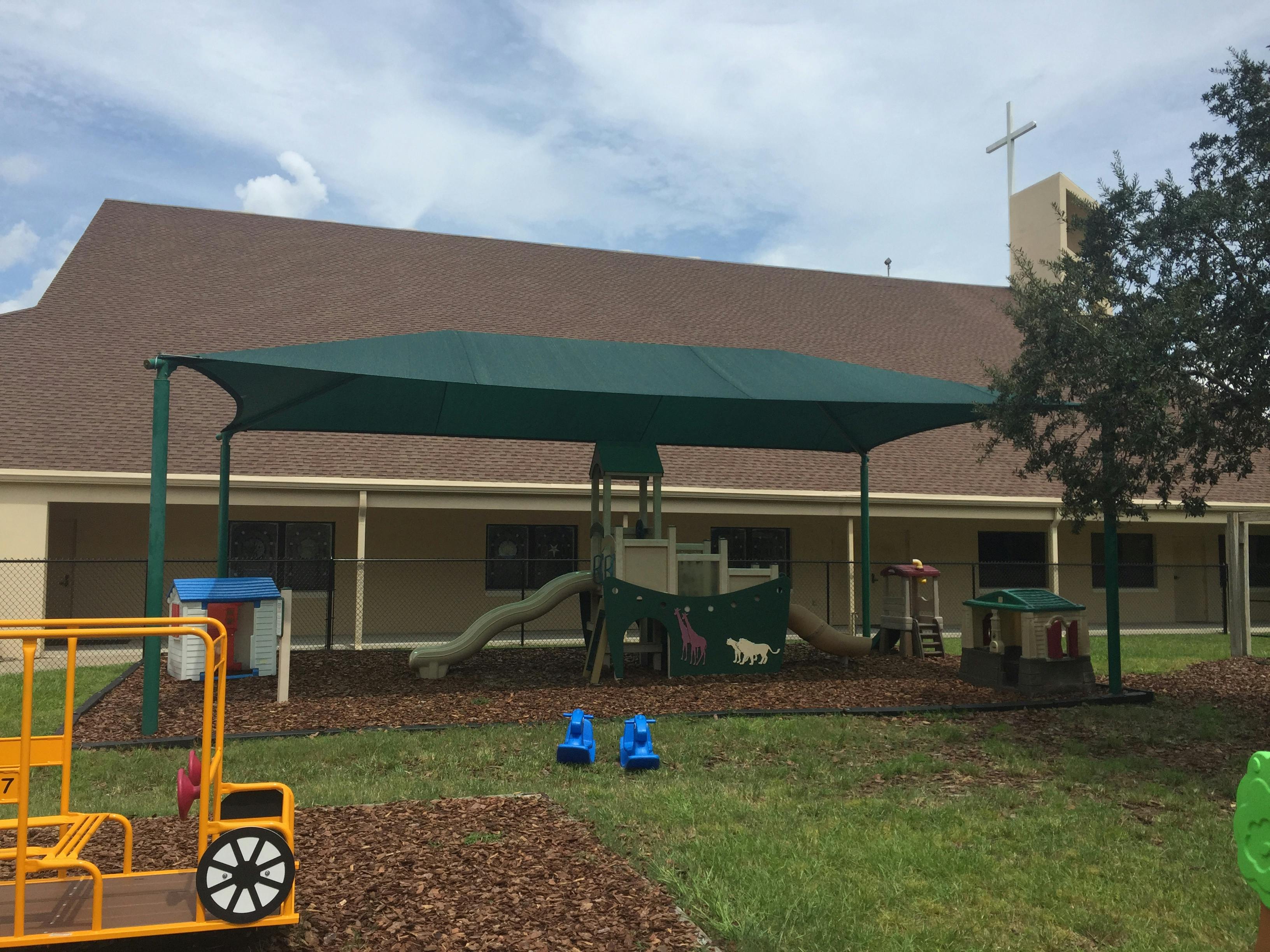 Outdoor playground with slides and a green shade canopy