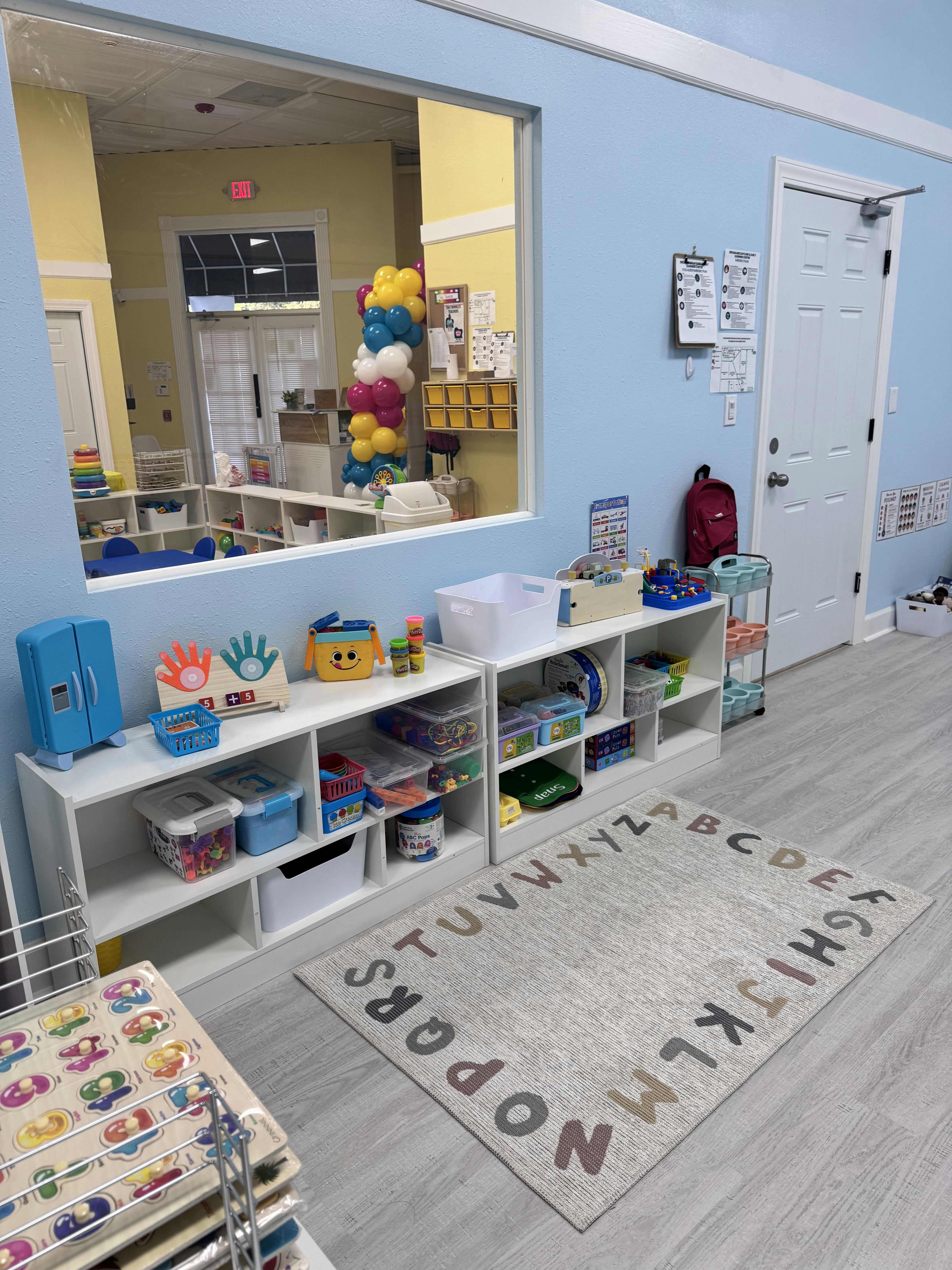 Classroom with shelves of toys and an alphabet rug